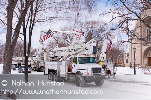 Several flags hang from cherry pickers as one drives off